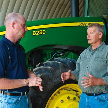 Two men talking in front of a tractor